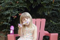 Fille souffler des bulles dans le jardin — Photo de stock
