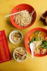 Bowls of Chinese noodle soup and menu on table — Stock Photo