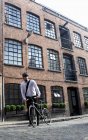 Uomo d'affari spingendo bicicletta all'aperto — Foto stock