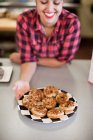 Junge Frau hält Teller mit frisch gebackenem Kuchen in Bäckerei — Stockfoto