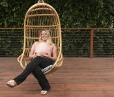 Pregnant woman relaxing in garden swing chair — Stock Photo