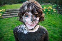 Boy smiling face covered in mud, focus on foreground — Stock Photo