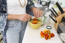 Cropped view of woman garnishing food with flowers — Stock Photo