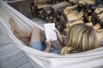 Женщина читает книгу в гамаке, Амагансетт, Нью-Йорк, США — стоковое фото