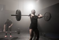 Young woman lifting barbell — Stock Photo