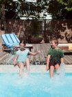 Menino e menina salpicando na piscina — Fotografia de Stock