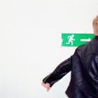 Boy walking past exit sign — Stock Photo