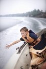 Хлопчик-підліток дістається до води з човна — стокове фото