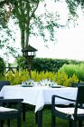 Стол и стулья на террасе ресторана рядом с зелеными растениями — стоковое фото