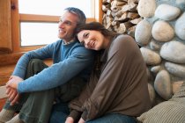 Mid adult couple sitting in log cabin — Stock Photo