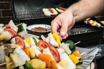 Man grilling vegetable skewers — Stock Photo