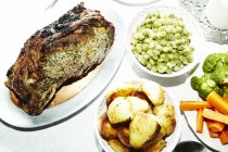 Жареное мясо с картошкой, морковью, брокколи и широкими бобами на столе — стоковое фото