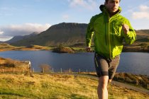 Escursionista correre su per la collina erbosa — Foto stock