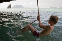 Ragazzo che gioca sulla corda sopra l'acqua — Foto stock