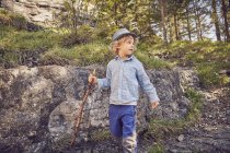 Um menino, segurando pau, explorando a floresta — Fotografia de Stock