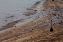 Shovel in sand on oily beach — Stock Photo