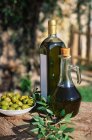 Fresh olives and oil bottles on table — Stock Photo