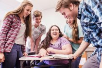 High school teenagers laughing and talking around desk — Stock Photo