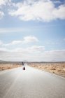 Mujer rodando equipaje en carretera rural - foto de stock