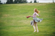 Портрет молодої жінки, що танцює в парку, тримає червоні високі підбори — стокове фото