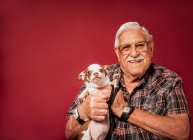 Homem sênior segurando cão pequeno — Fotografia de Stock