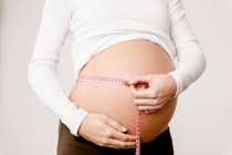 Imagem cortada da mulher grávida medindo sua barriga — Fotografia de Stock