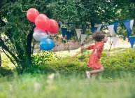 Mädchen hält Ballons im Freien — Stockfoto