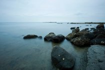 Rocas en aguas tranquilas de la costa - foto de stock