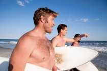 Tres surfistas en la playa - foto de stock