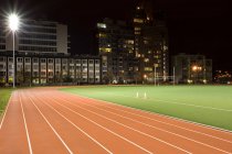 Pista de corrida e campo de futebol iluminado à noite — Fotografia de Stock