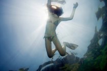 Low angle underwater view of girl snorkeling in tropical waters — Stock Photo