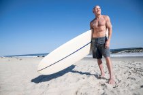 Surfista in piedi con tavola da surf sulla spiaggia — Foto stock
