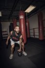 Boxer masculino se preparando para levantar kettlebell no ginásio — Fotografia de Stock