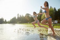 Chicas en bikini saltando al lago, Seattle, Washington, Estados Unidos - foto de stock