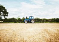 Tractor driving in tilled crop field — Stock Photo