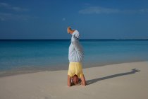 Woman practicing yoga on tropical beach — Stock Photo