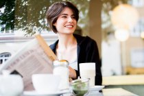 Mujer leyendo periódico en la cafetería - foto de stock