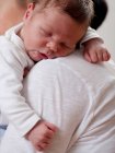 Мати, що носить сплячого немовляти, зосередьтеся на передньому плані — стокове фото