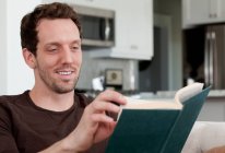 Homem adulto médio sentado em casa, livro de leitura — Fotografia de Stock