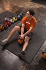 Fisiculturista descansando no tapete de exercício no ginásio — Fotografia de Stock