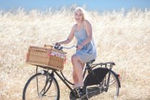 Mulher andar de bicicleta em grama alta — Fotografia de Stock