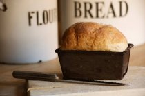 Primer plano de pan en lata de pan con cuchillo - foto de stock