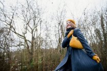 Lächelnde Frau geht im Wald spazieren — Stockfoto