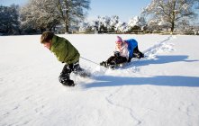 Дети играют на санях в снегу — стоковое фото