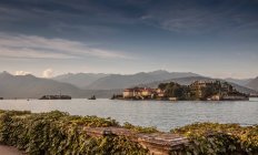 Old village buildings on island in lake with hills on background — Stock Photo