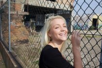 Femme souriante appuyée contre la clôture — Photo de stock