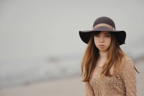 Chica adolescente sentada en la playa de arena - foto de stock