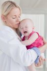 Doctor hugging crying baby, selective focus — Stock Photo