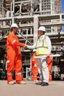 Workers shaking hands at oil refinery — Stock Photo