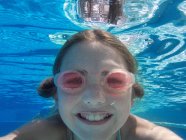 Close up underwater portrait of girl wearing goggles in swimming pool — Stock Photo
